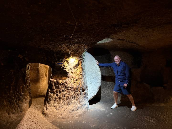Visitor poses inside a dimly lit underground chamber of Cappadocia’s carved city.