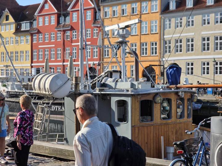 Harbor scene with colorful 17-century waterfront buildings and a wooden boat moored in front.