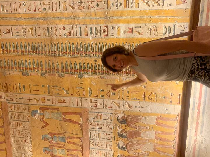Visitor points at colorful hieroglyphics inside an ancient Egyptian tomb