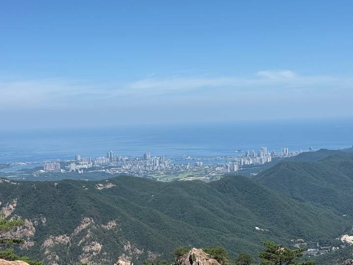 View from mountain over coastal city skyline beside vast blue sea