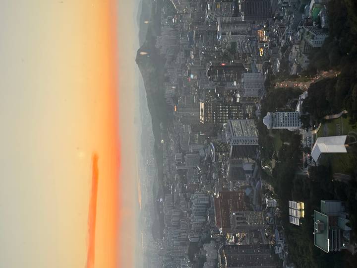 High viewpoint over sprawling city at sunset with orange sky glow