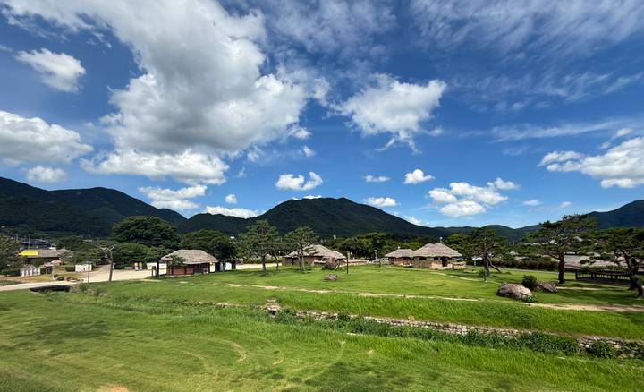 Traditional Korean folk village of thatched houses set among green mountains and blue sky