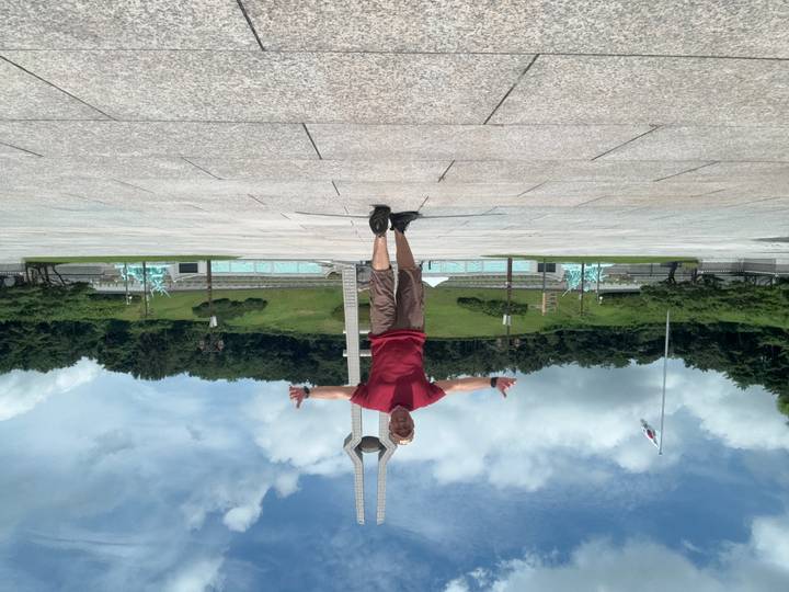 Man posing arms outstretched on large plaza before monument and fountains