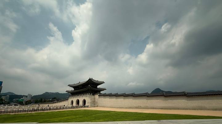 Expansive view of Gyeongbokgung Palace gate and wall under dramatic clouds