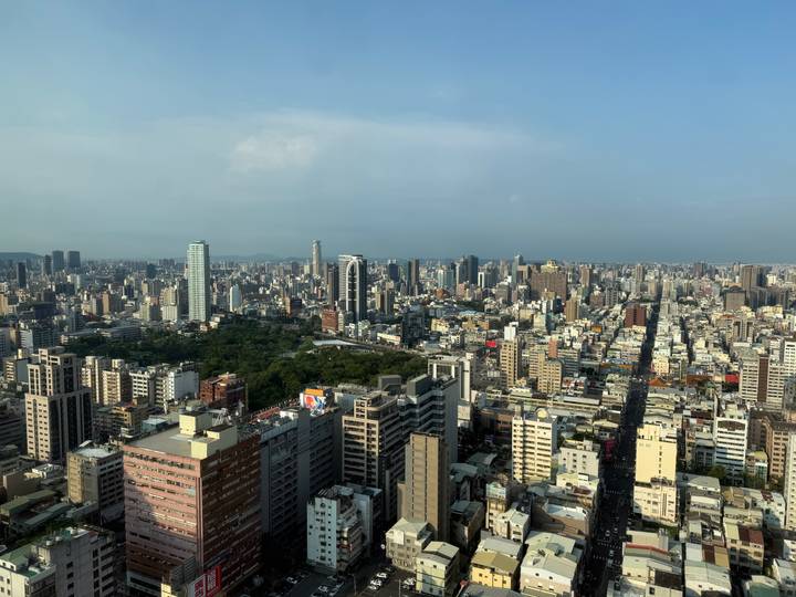 Panoramic skyline of dense city buildings with small central park under hazy sky