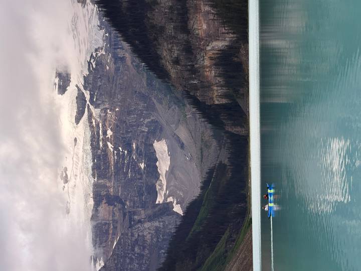 Canoe floats on the emerald waters of Lake Louise below towering glacier-clad cliffs