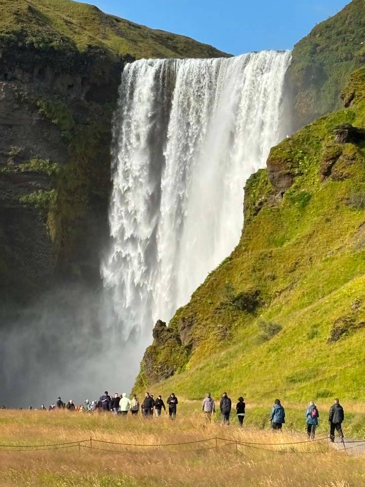 Powerful white waterfall plunging down a moss-covered cliff, mist rising at its base.