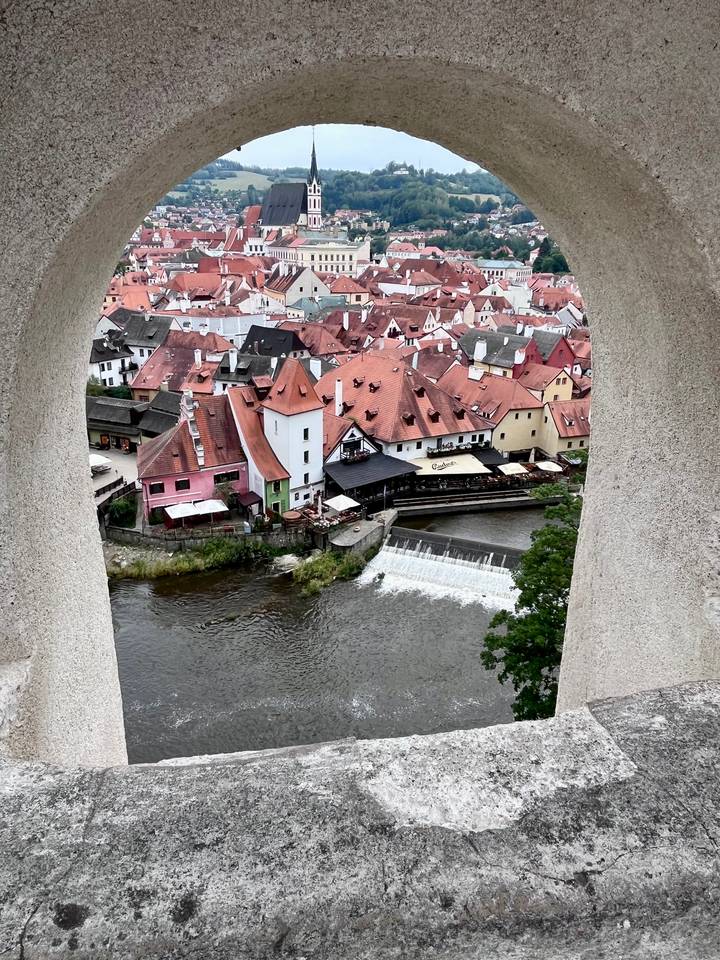 Colorful tiled rooftops of Cesky Krumlov old town hugging river bend and small weir