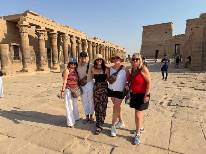 Group of travelers posing happily amid ancient colonnades on an island temple.