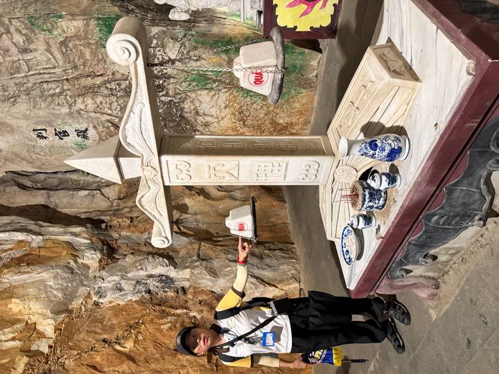 Stone balance scale altar with Chinese characters inside a cave shrine.