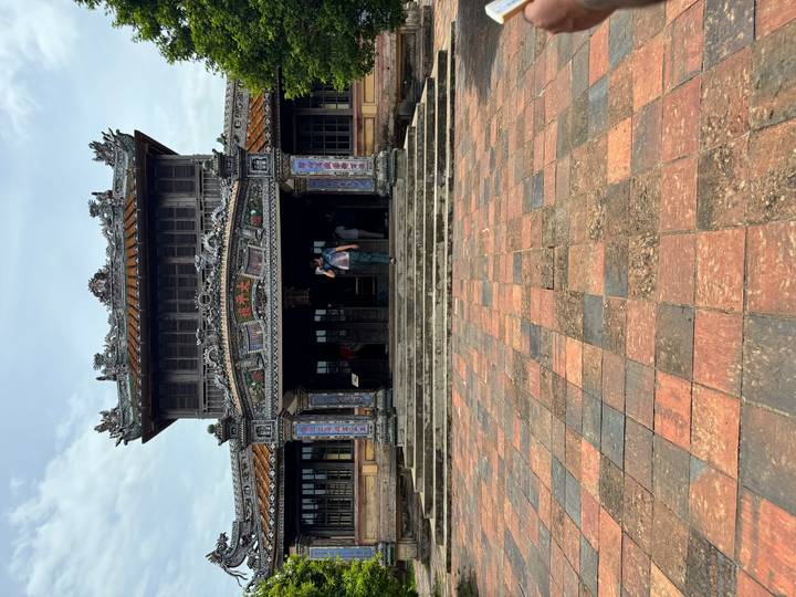 Visitor ascending stone steps toward elaborately carved ancient gate of Hue Citadel.