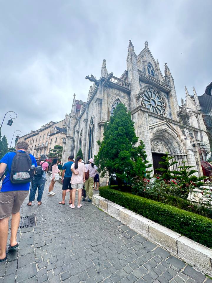 Stone gothic-style cathedral façade at Sun World Ba Na Hills with tourists walking by.