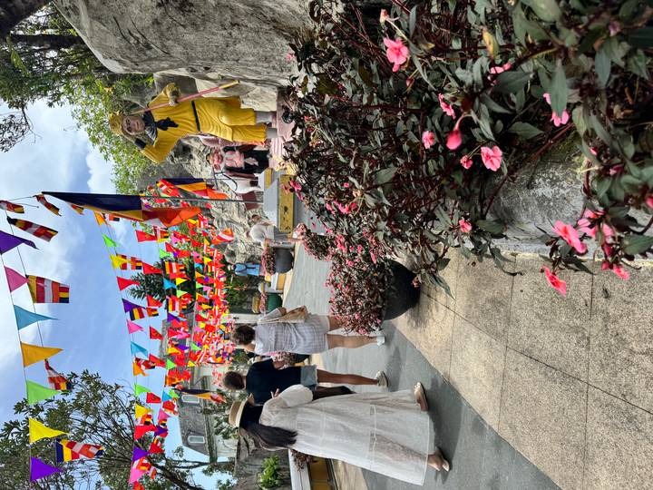 Colorful flag-lined pathway crowded with visitors and playful statues at Ba Na Hills festival area.