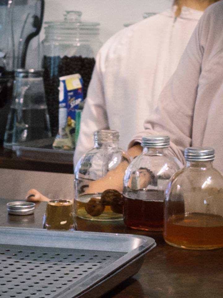 Close-up of glass bottles and a person preparing drinks behind a counter.