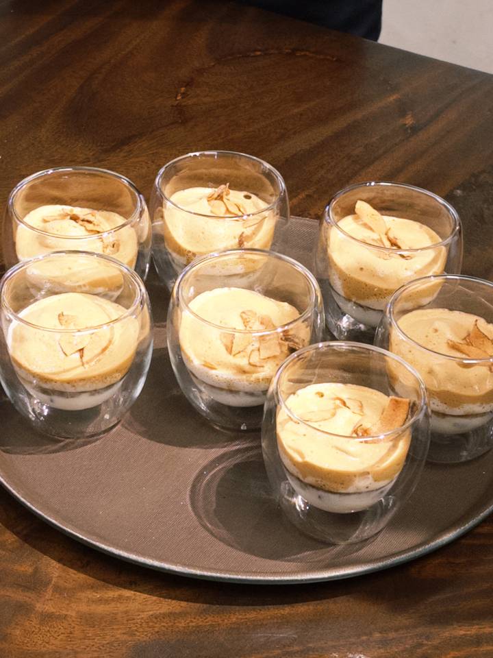 Row of rounded glasses filled with layered egg coffee topped with crunchy chips.