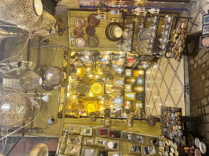 Glowing brass and metal lanterns densely displayed inside a traditional Moroccan lamp shop.