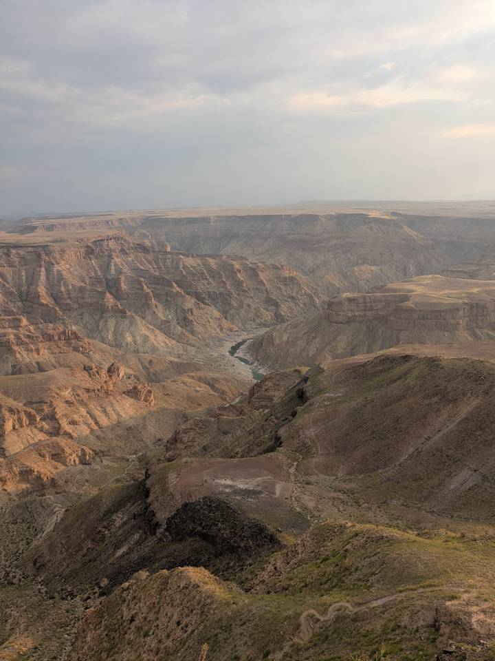Vast panorama of Fish River Canyon with layered cliffs and a winding river far below.