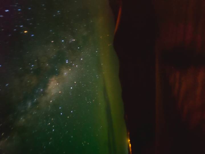 Blurry long-exposure image of a starry night sky with Milky Way over dark dunes.