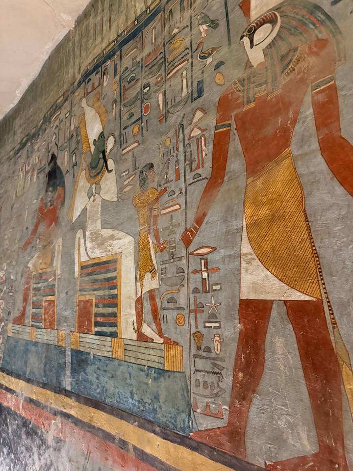 Detail of colorful ancient Egyptian wall art portraying deities and symbolic motifs.