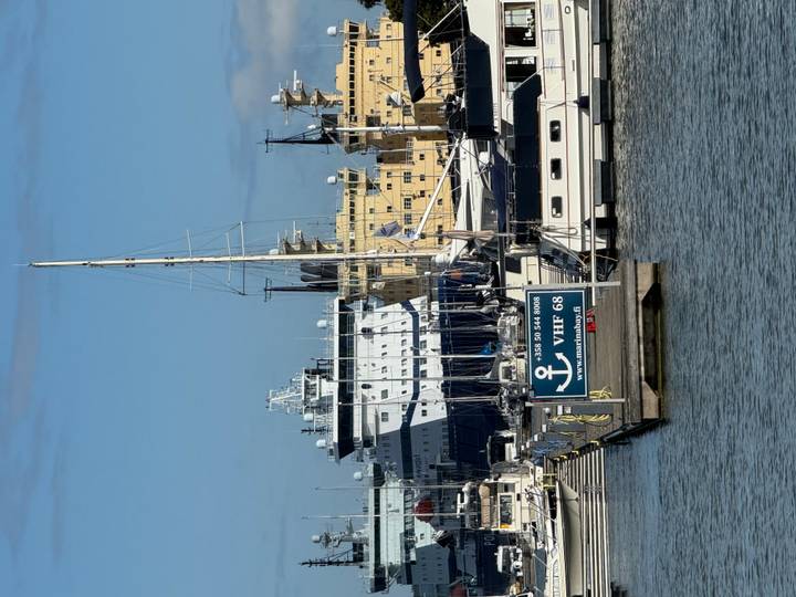 Harbor view with yachts, icebreakers and Finnish signage under bright blue sky.