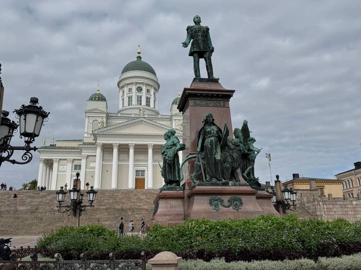 Neoclassical Helsinki Cathedral and bronze Alexander II statue dominate Senate Square beneath grey clouds.