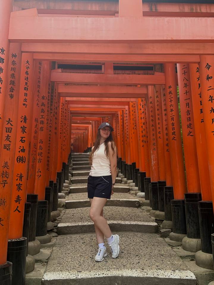 Traveler standing among the endless red torii gates of Fushimi Inari Shrine