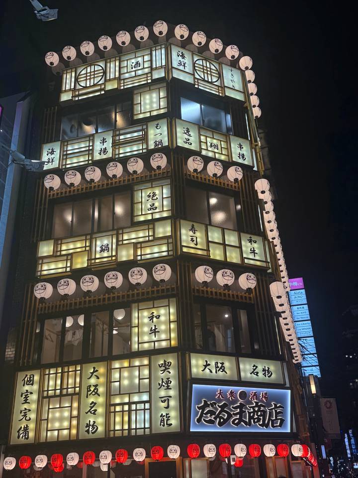 Night-time view of a multi-storey Japanese restaurant facade, lit by square lanterns and kanji signs.