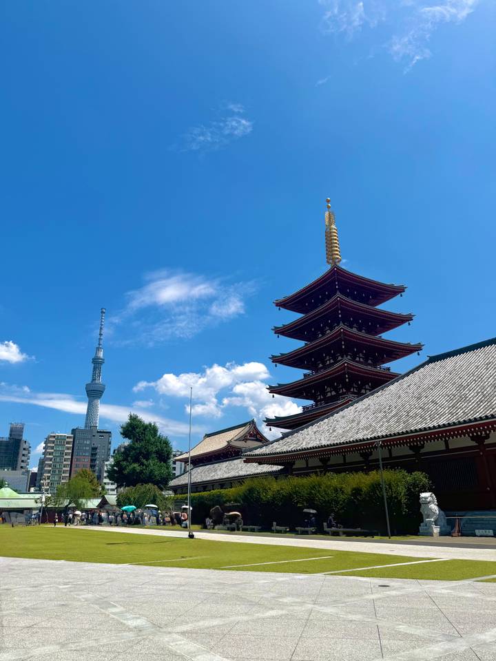 Five-storey pagoda of Senso-ji Temple framed against a bright blue sky with Tokyo Skytree in the background.
