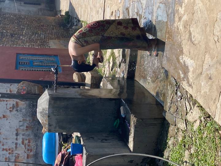 Woman rinsing her face at a communal outdoor tap in a rural village.