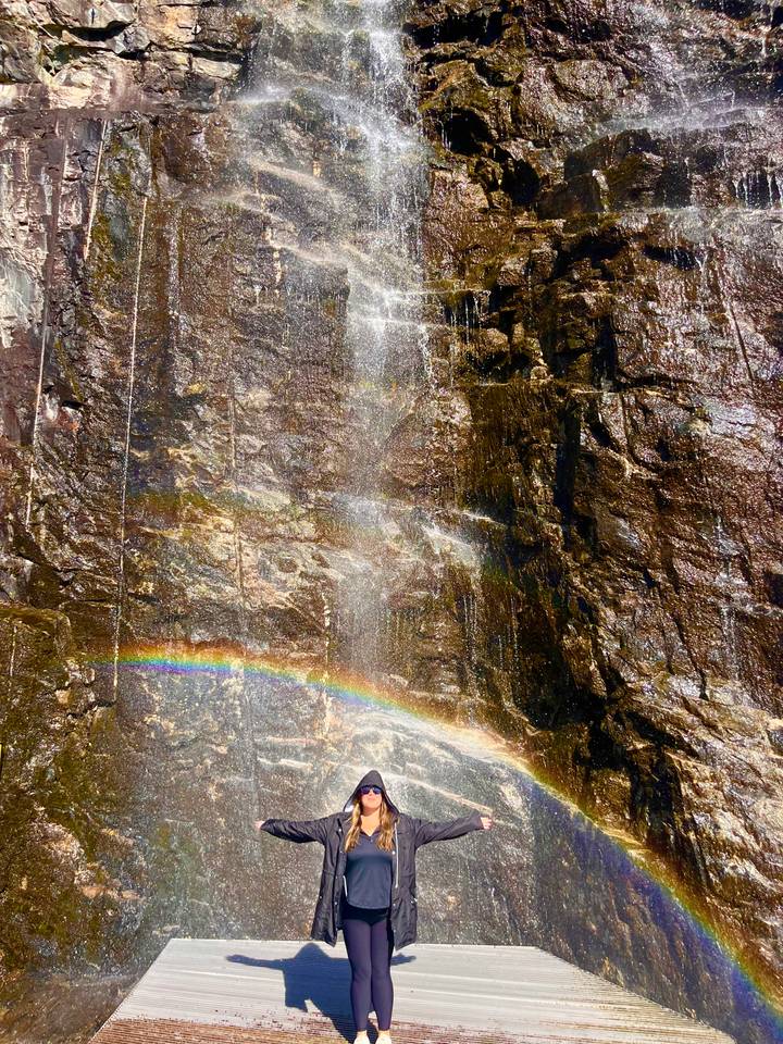 Close view of a rock face waterfall with mist creating a vibrant rainbow arc.