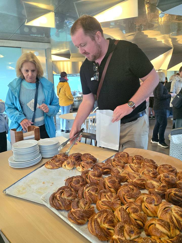 Travellers select fresh pastries from a buffet table inside a café.