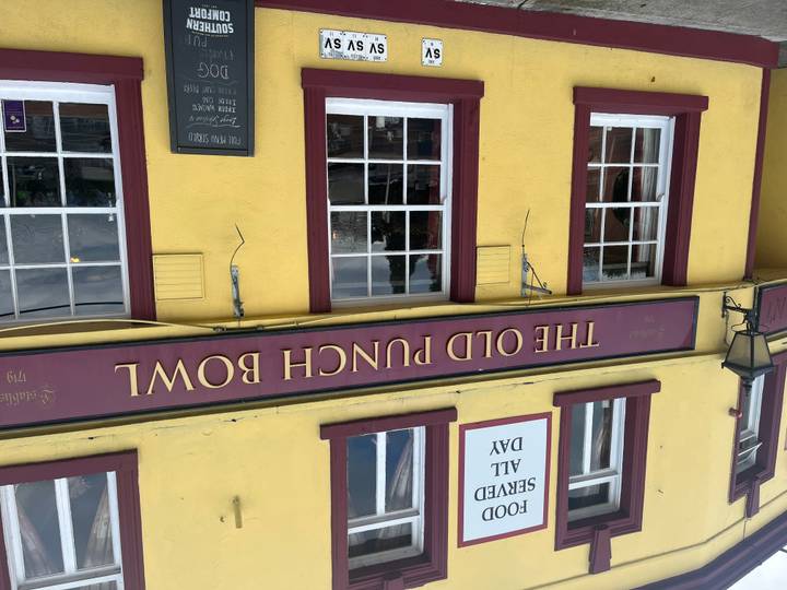 Bright yellow facade of The Old Punch Bowl pub with sash windows and maroon signage.