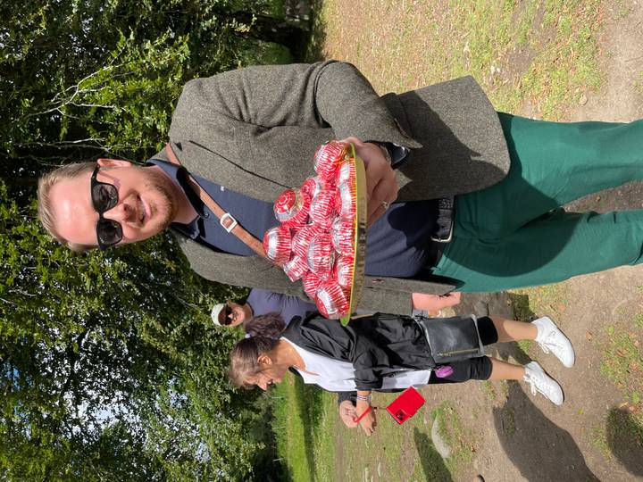 Guide presents a tray piled high with individually wrapped chocolates to tour guests in a park.