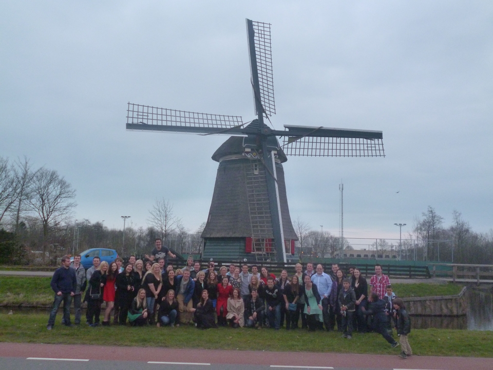 Grand groupe de personnes posant devant un moulin à vent.