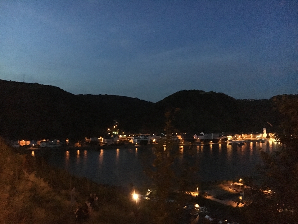 Vue nocturne d'une ville riveraine avec des lumières se reflétant sur l'eau.