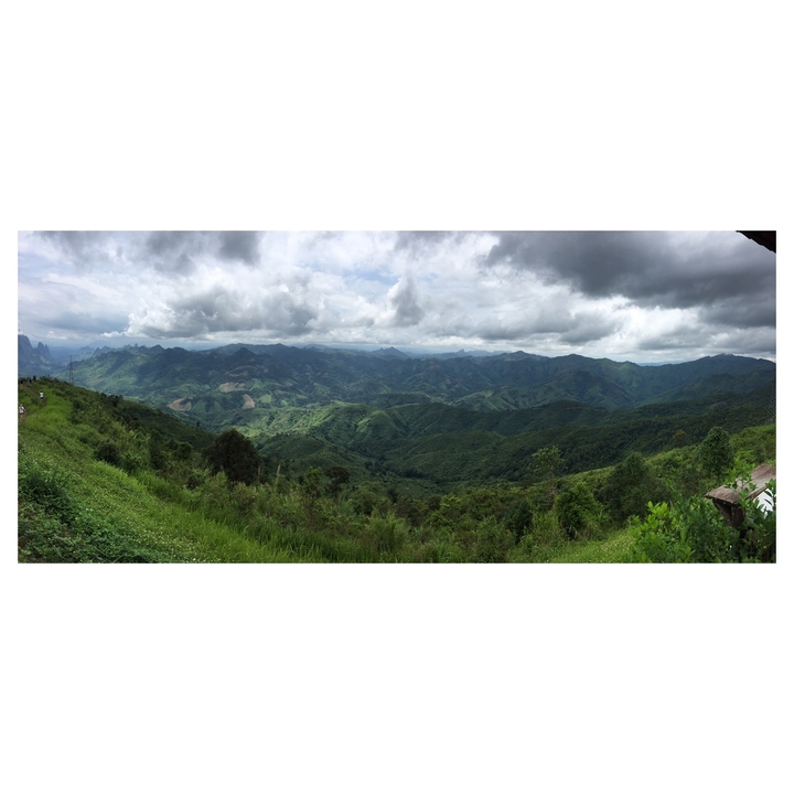 Vue panoramique de montagnes verdoyantes sous un ciel nuageux.