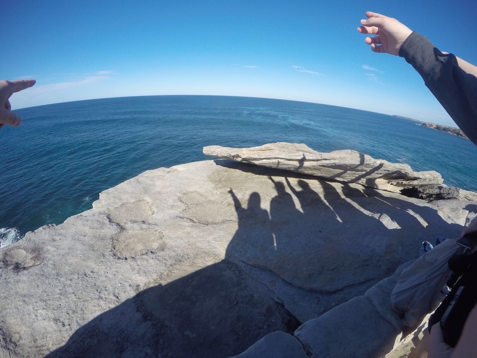 Silhouetted people on a rocky cliff overlooking the ocean.