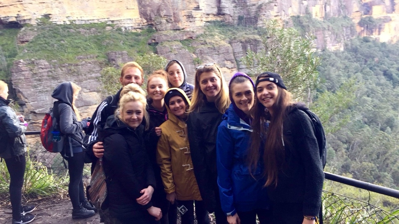 Group of people posing in front of a cliff face.