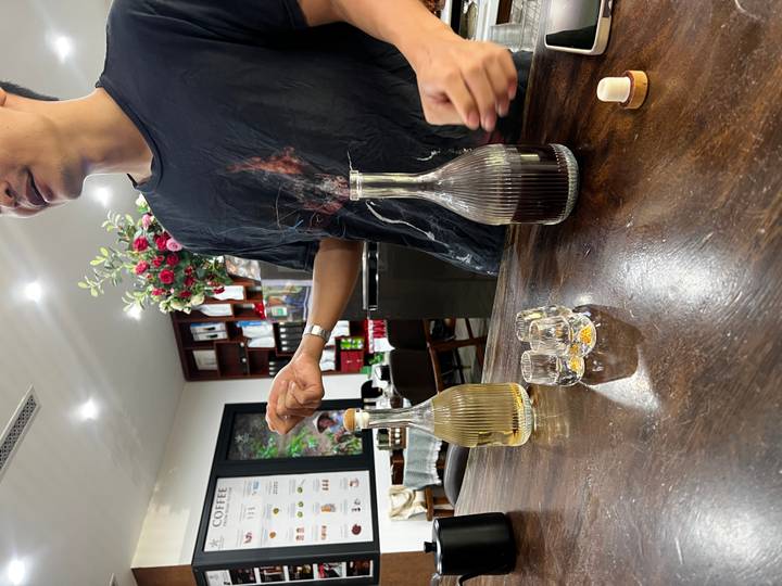 Coffee workshop host presents two carafes of coffee on a wooden table alongside tasting glasses.