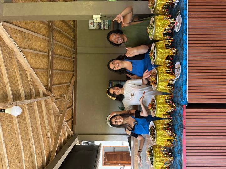 Smiling women showing off colourful Indonesian dishes during a cooking class.