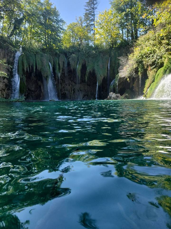Clear turquoise pool with cascading waterfalls framed by moss-covered cliffs.