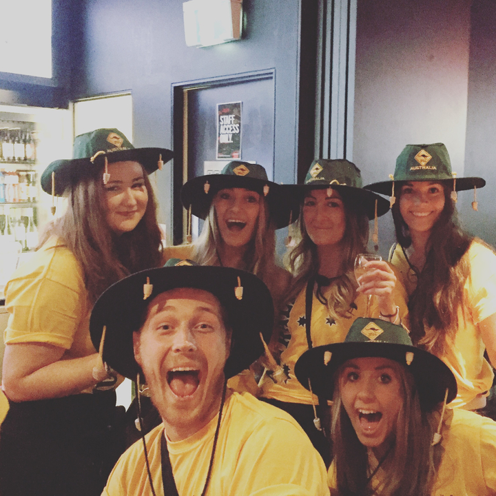 Group of people wearing Australian hats, posing indoors.