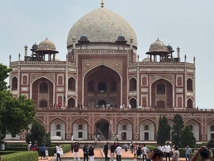 Imposing Humayun's Tomb in red sandstone and white marble with visitors on the upper terrace.