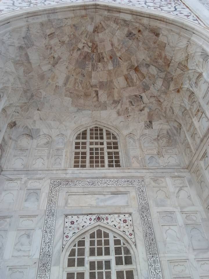 Pale marble wall with decorative arches and calligraphy panels inside the Taj Mahal complex.