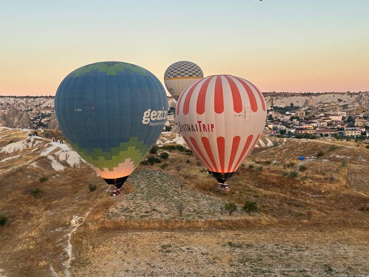 Colorful hot air balloons lift over Cappadocia’s arid hills at sunrise.