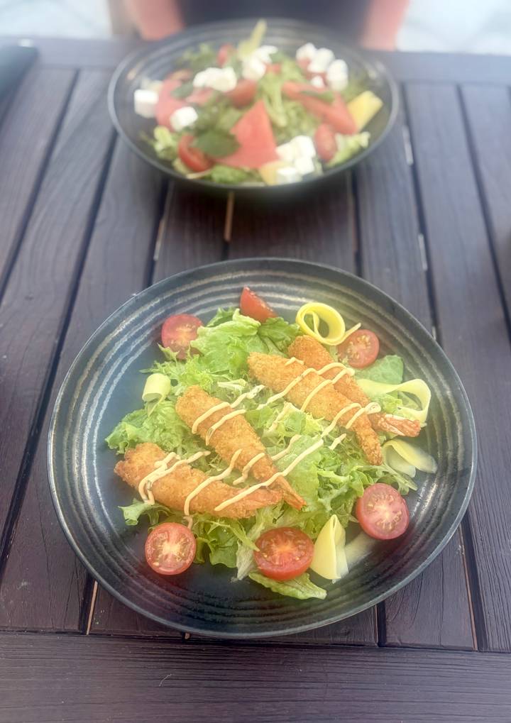 Fresh salad topped with crispy breaded fish strips, lettuce and cherry tomatoes.