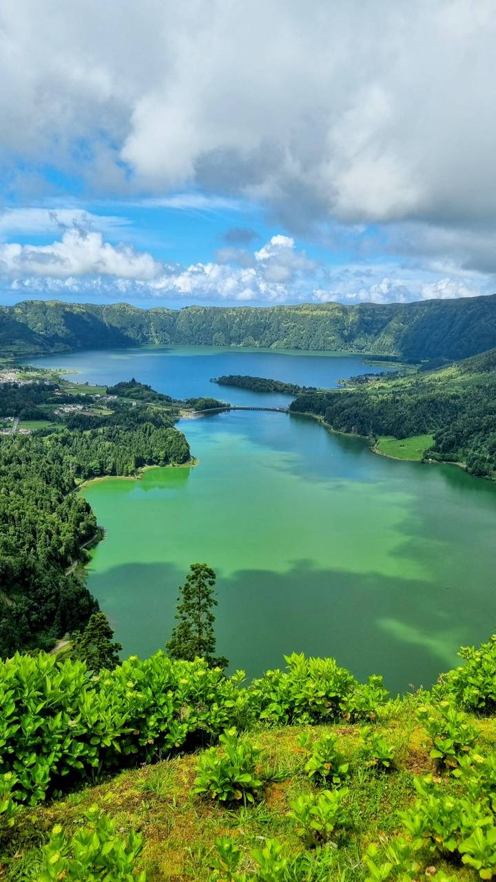 Aerial view of twin-coloured Sete Cidades lakes separated by a narrow bridge.