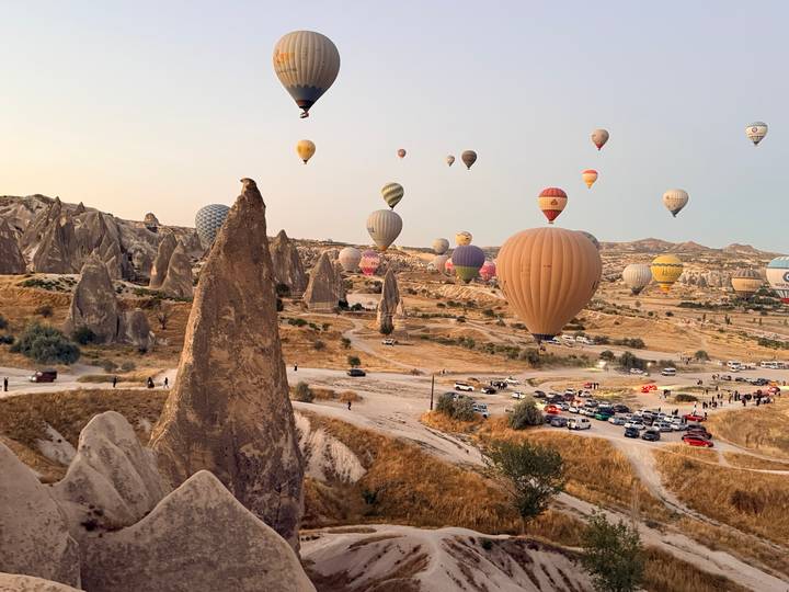 Dozens of colourful hot-air balloons rise over Cappadocia’s fairy-chimney rock landscape at dawn.
