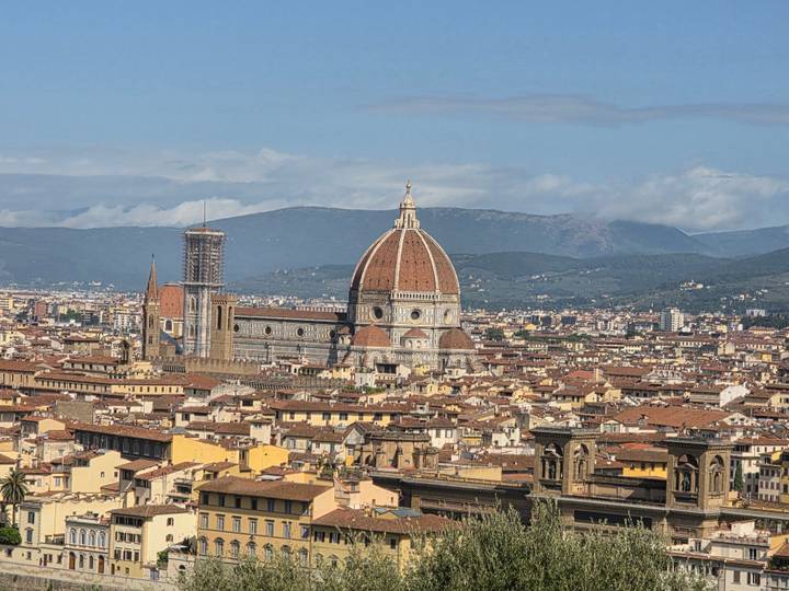 Panoramic view of Florence with the iconic red-tiled Duomo dome rising above the city rooftops.