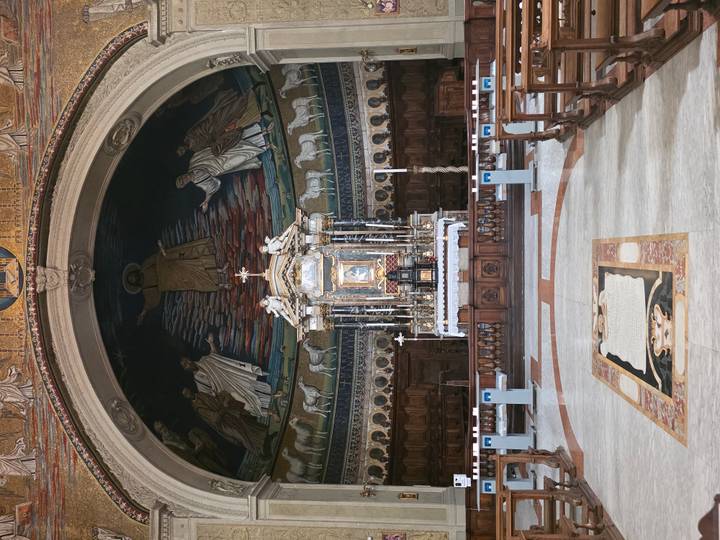 Elegant church apse featuring a mosaic Christ figure above a richly decorated altar.